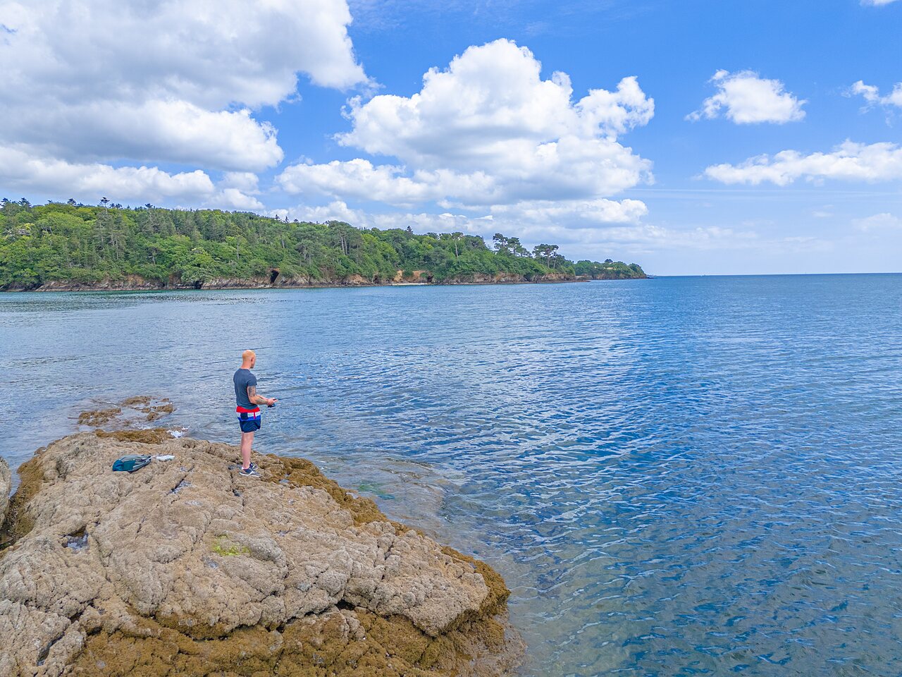 Fisherman on rocks by the sea at CAPFUN Saint Laurent campsite in LA FORET FOUESNANT (29).