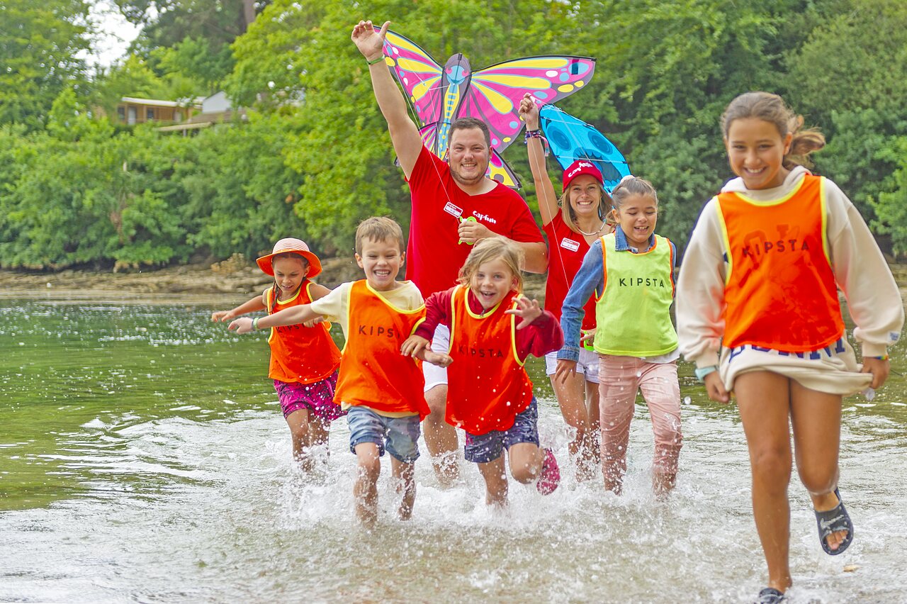 Children and animators playing in water with a kite at CAPFUN Saint Laurent campsite in LA FORET FOUESNANT (29).