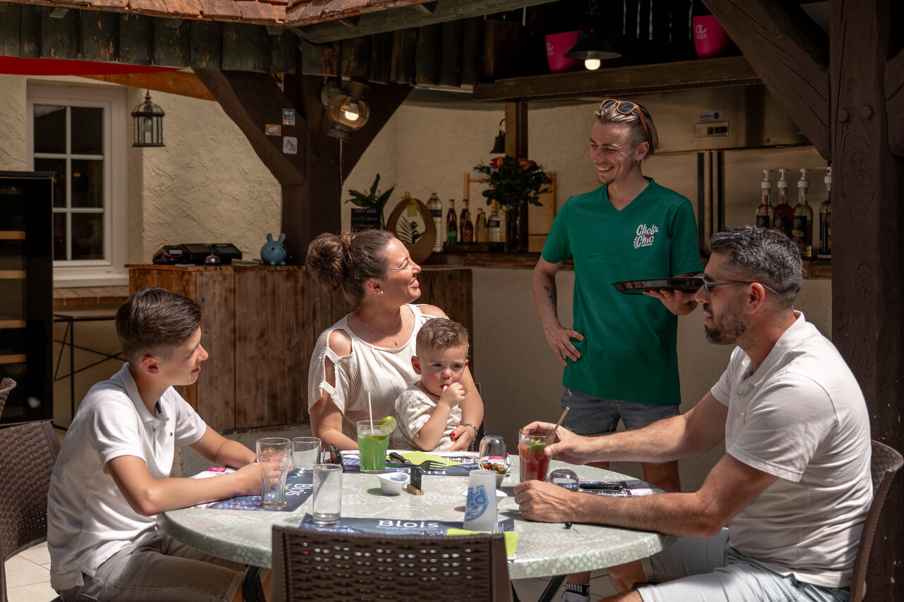 Lively outdoor restaurant-bar with family at CLICOCHIC Les Saules de Cheverny campsite.
