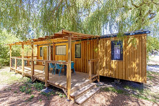 Wooden mobile home with covered deck and outdoor furniture at CLICOCHIC Les Saules de Cheverny campsite in Cheverny (41).