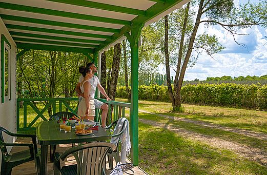 Covered mobile home terrace with couple at CLICOCHIC Les Saules de Cheverny campsite in Cheverny (41).