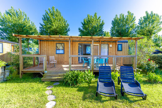 Wooden mobile home with covered terrace and chairs at CLICOCHIC Seulières campsite in Saint-Denis-d'Oléron (17).