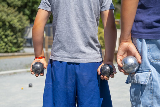 Children playing pétanque on the boules court at CLICOCHIC Seulières campsite in Saint-Denis-d'Oléron (17).