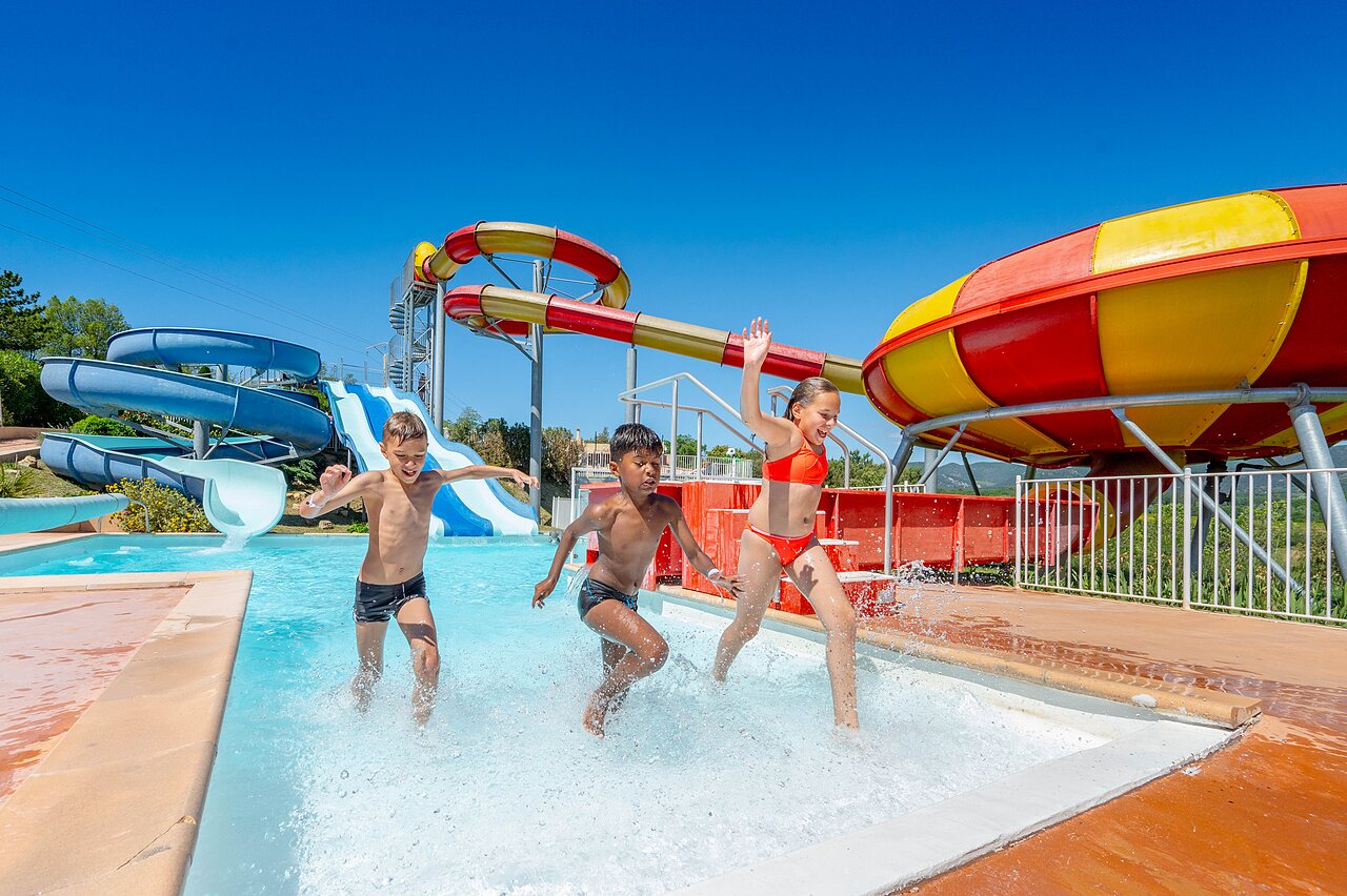 Children playing in the swimming pool with giant water slides at VAGUES OCEANES Soleil de Provence campsite in Saint-Romain-en-Viennois.