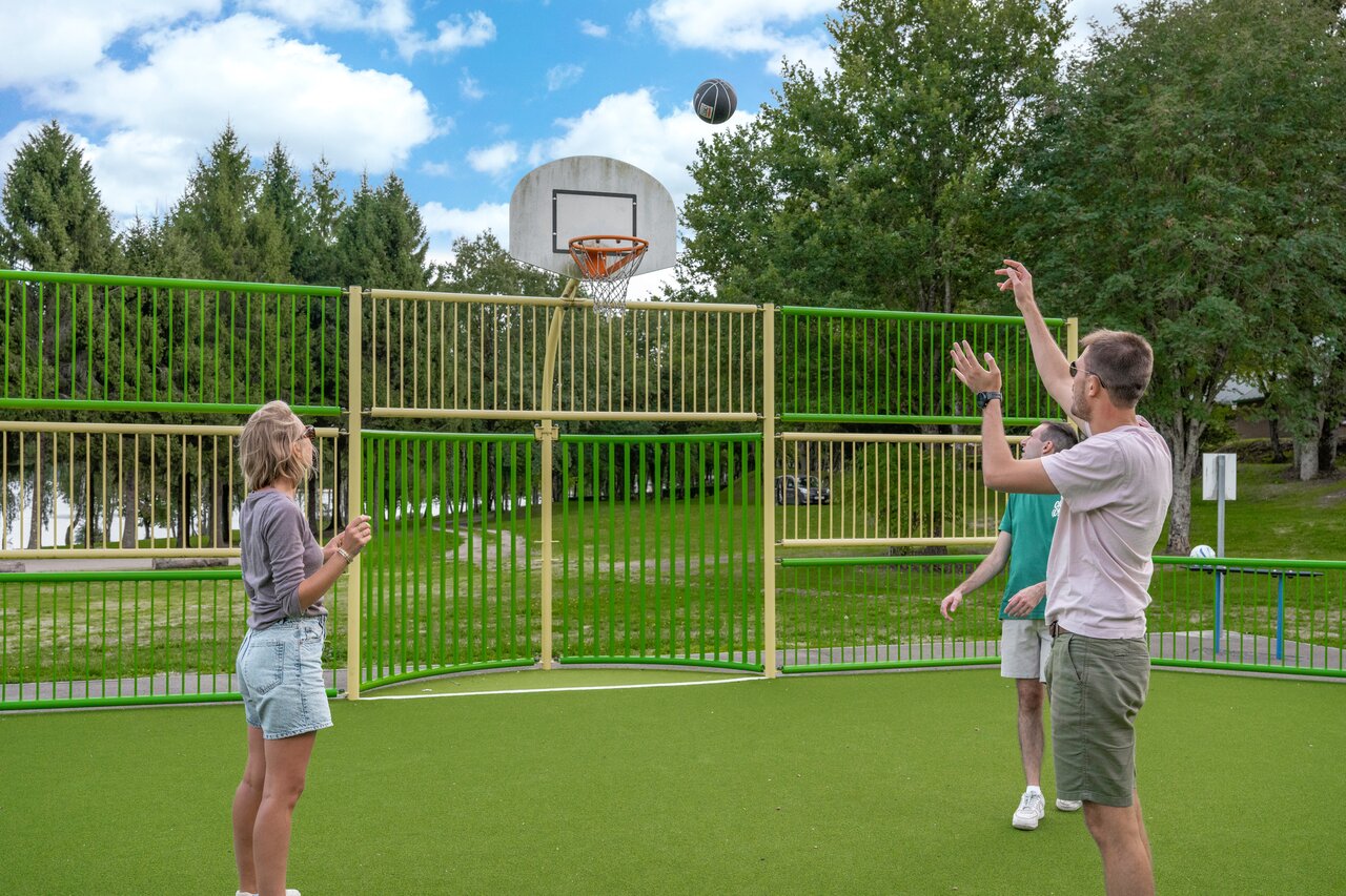 Multisport court with basketball hoop and players at camping CAPFUN Cenic in Canet-de-Salars.