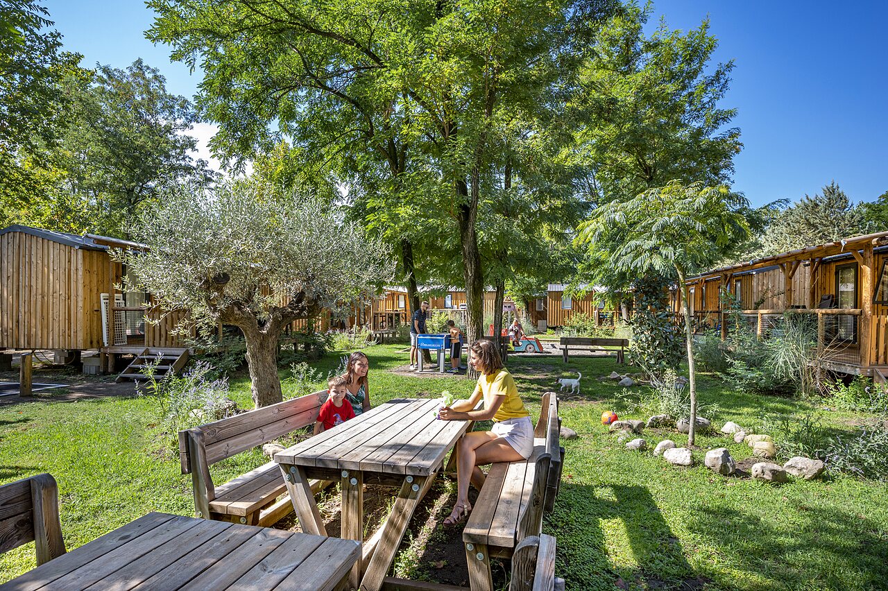 Family at picnic table near Mobile homes, nature and playground at CAPFUN Soubeyranne campsite in REMOULINS (30).