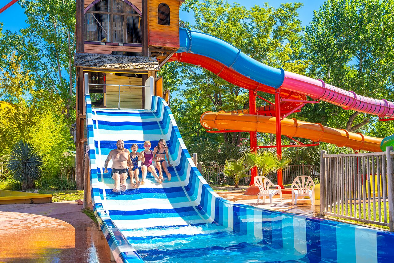 Family sliding down a large striped water slide at CAPFUN Soubeyranne campsite in REMOULINS (30).