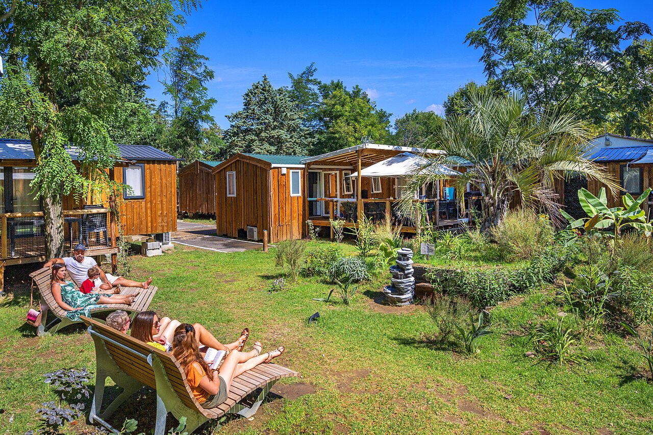 Wooden mobile homes, vacationers relaxing on sun loungers at CAPFUN Soubeyranne in REMOULINS (30).
