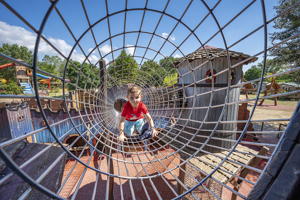 Child in metal play tunnel at CAPFUN Soubeyranne campsite in REMOULINS (30).