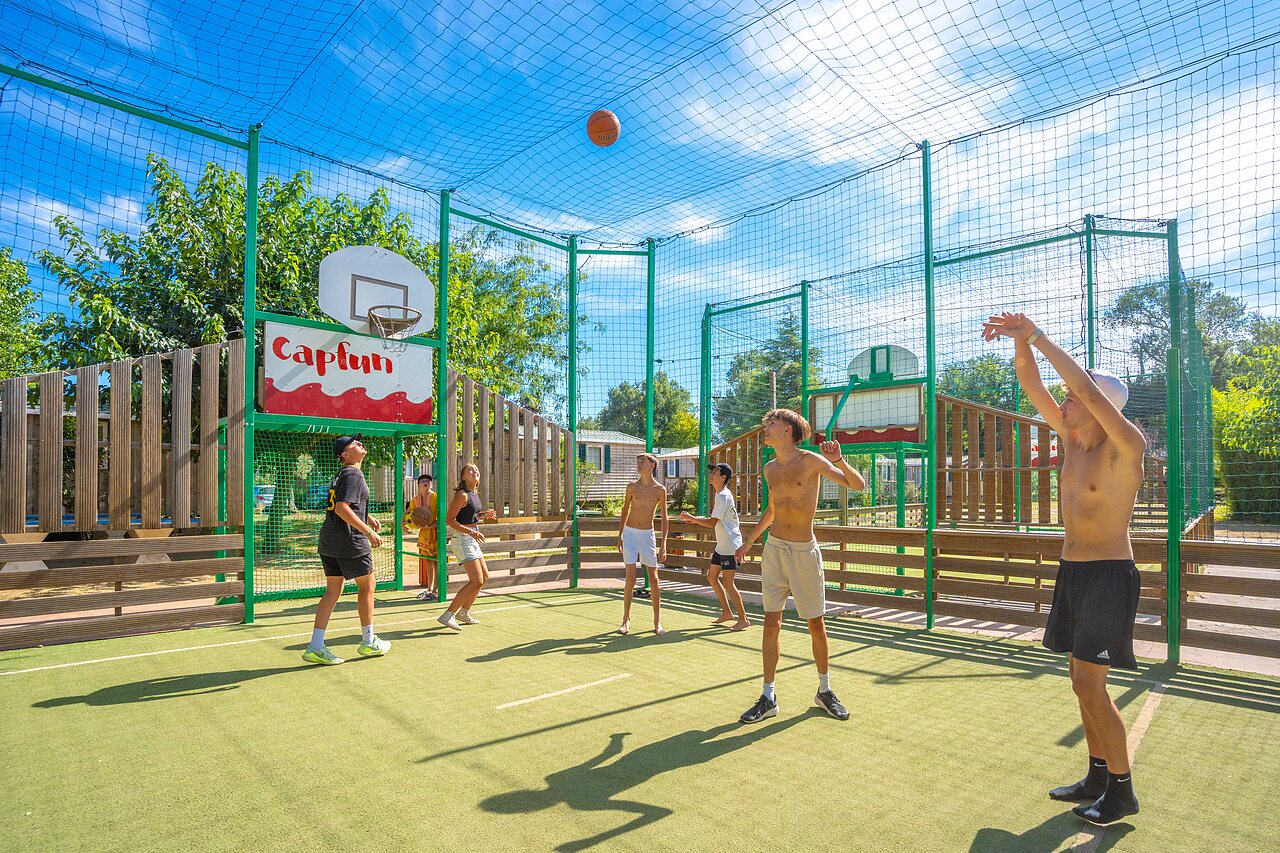Young people playing basketball on multisport court at CAPFUN Soubeyranne campsite in REMOULINS (30).