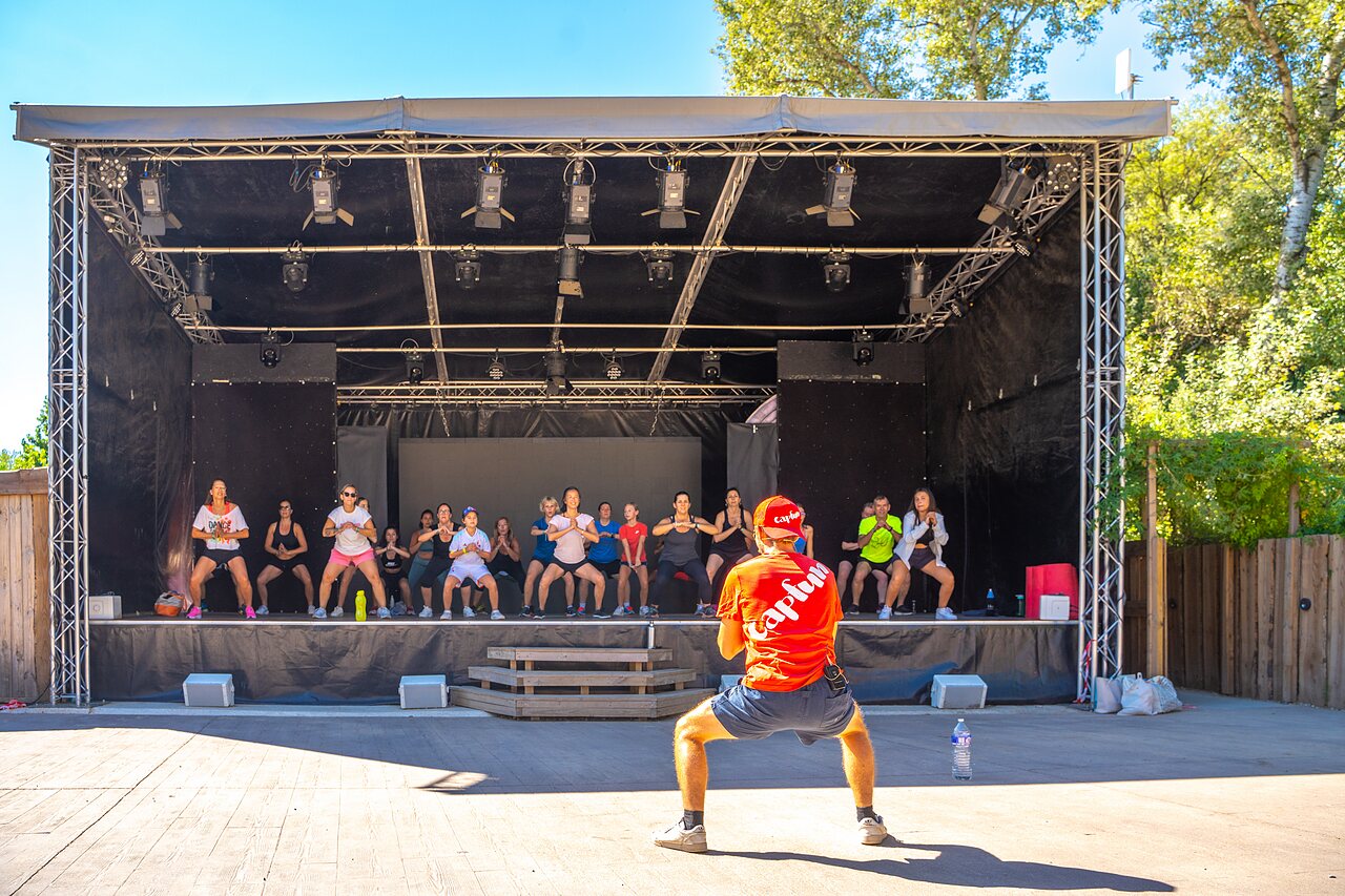 Group fitness class on outdoor stage at CAPFUN Soubeyranne, REMOULINS (30).