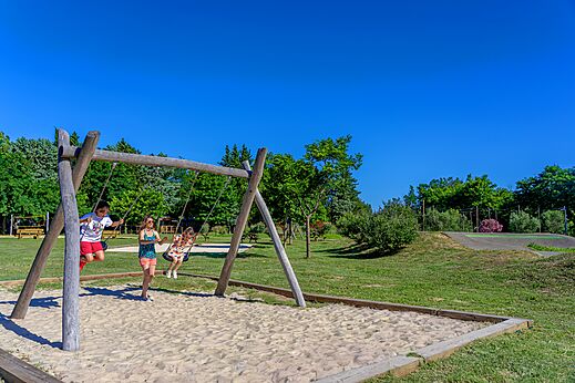 Wooden swing set with children playing in sand at CAPFUN Soubeyranne campsite in REMOULINS (30).