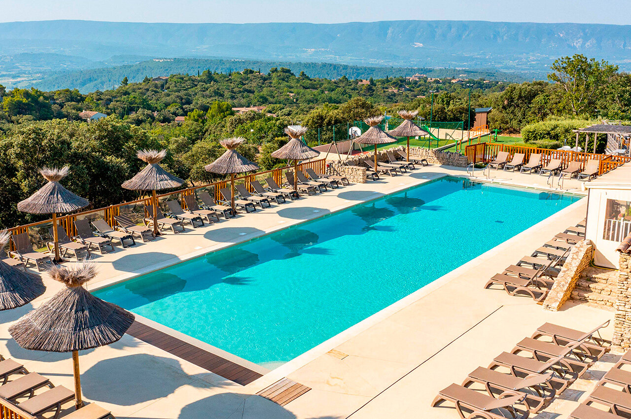 Large outdoor swimming pool with sun loungers, parasols, panoramic view at CLICOCHIC Les Sources de Gordes campsite in GORDES (84).