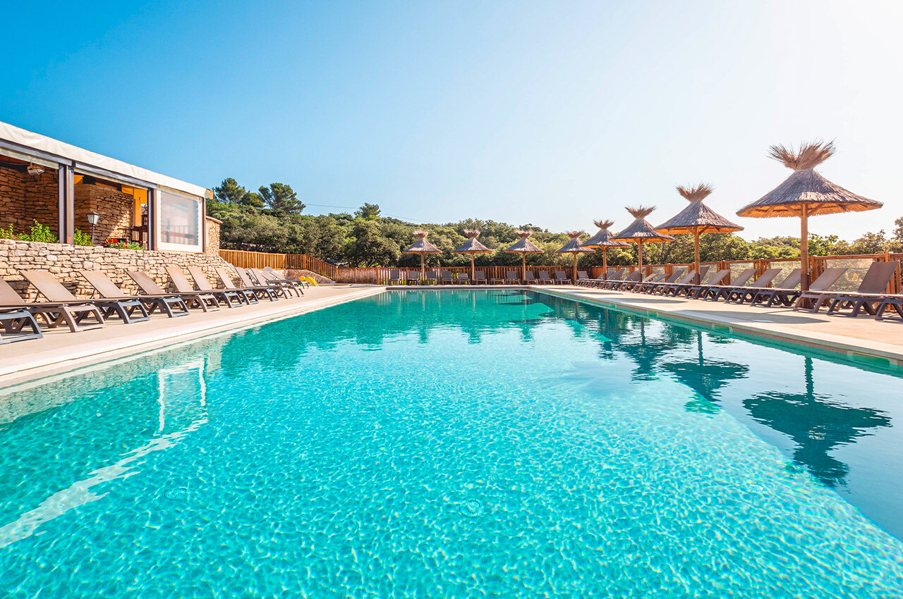 Outdoor pool, sun loungers, parasols at CLICOCHIC Les Sources de Gordes campsite in GORDES.