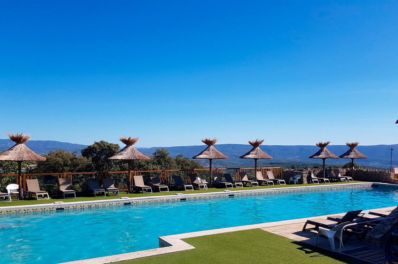 Outdoor swimming pool, sun loungers, straw parasols at camping CLICOCHIC Les Sources de Gordes in GORDES (84).
