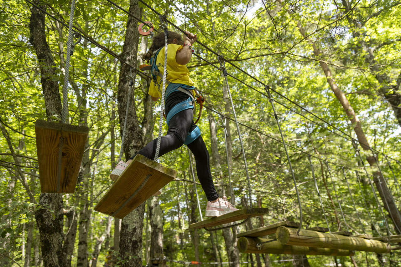 Child on adventure course in forest, rope bridge, camping CLICOCHIC Comps.