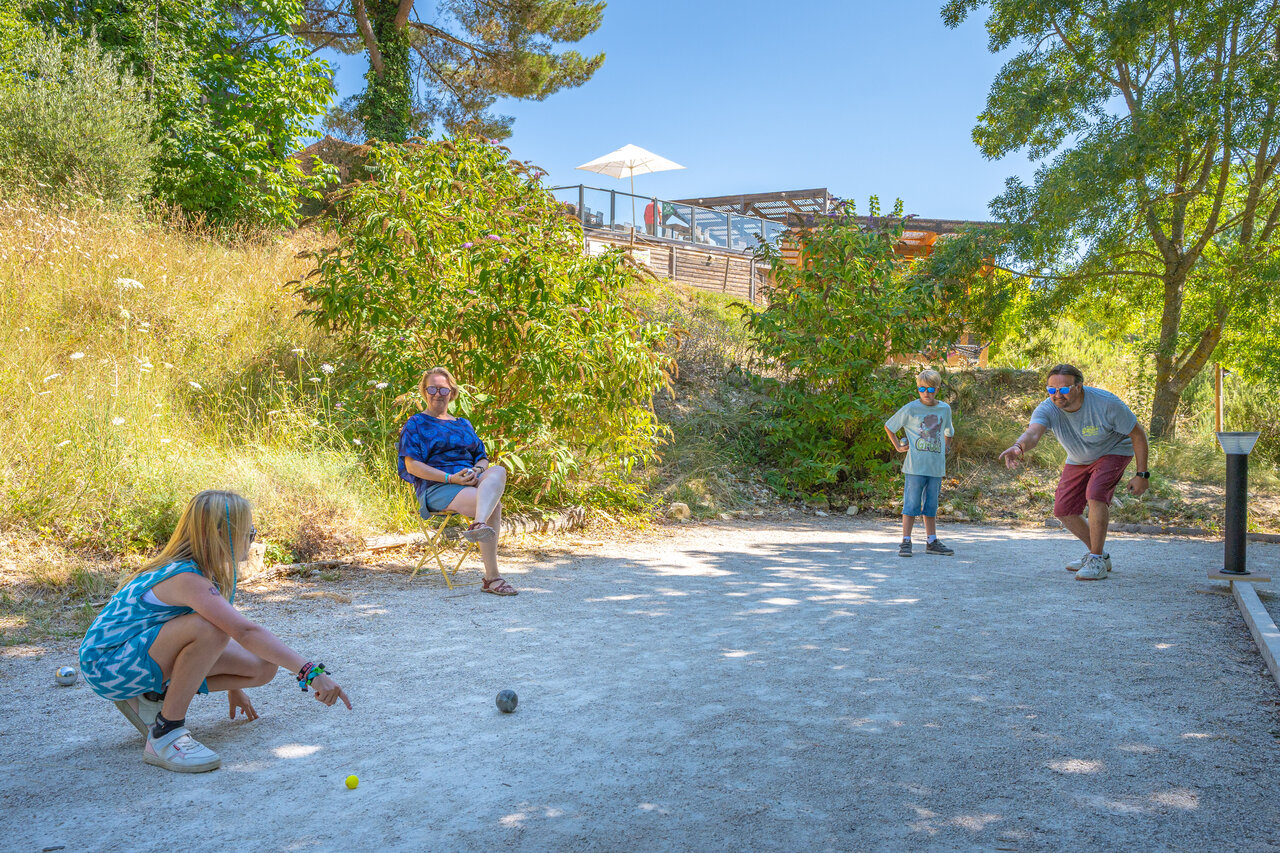 Family playing p�tanque on court at camping CLICOCHIC Source du Jabron.