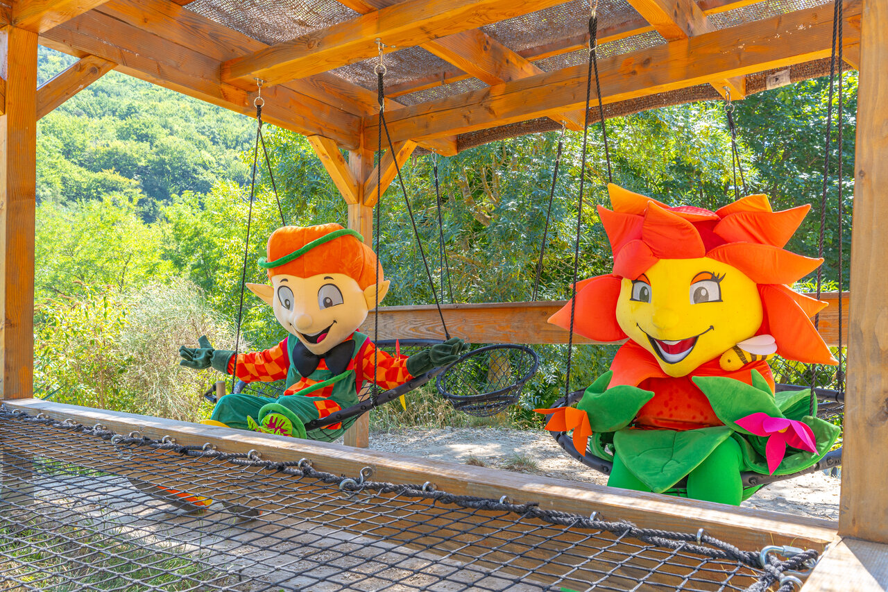 Smiling mascots on swings, playground at camping CLICOCHIC Source du Jabron.