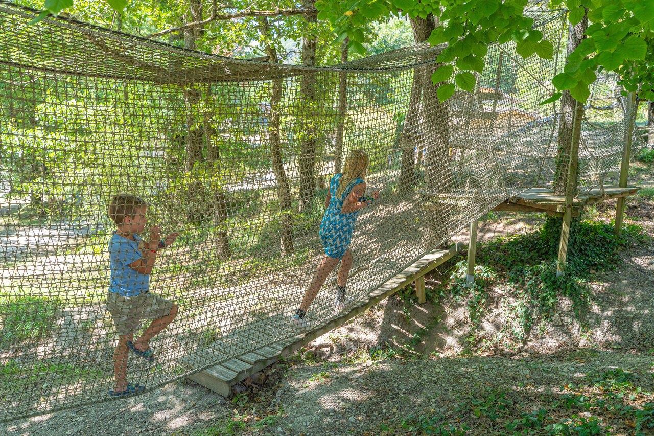 Kids on net adventure course, playground at camping CLICOCHIC Source du Jabron.
