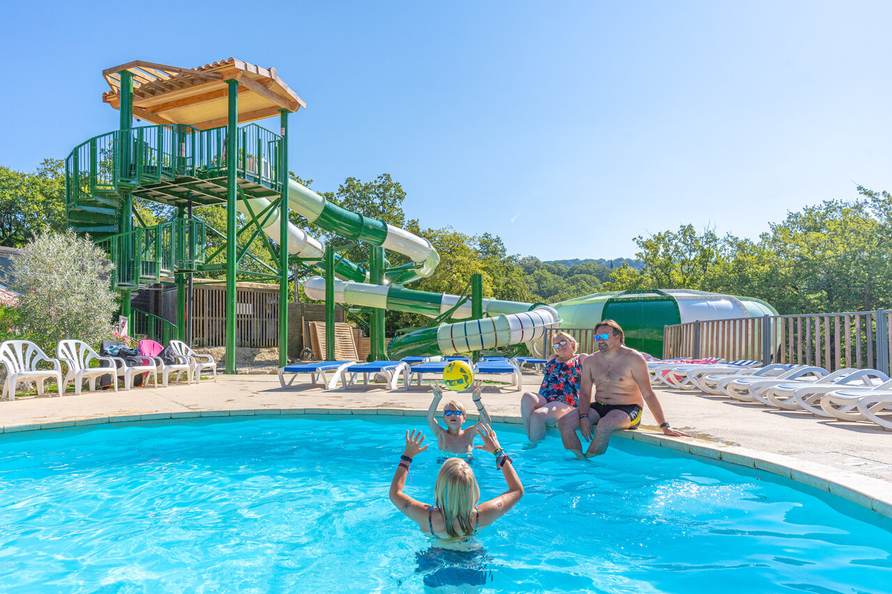 Family playing in the swimming pool with giant water slides at CLICOCHIC Source du Jabron campsite in Comps (26).