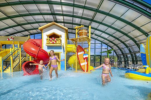 Children playing in indoor water park with slides at CAPFUN Vakantiepark Capfun het Stoetenslagh campsite in Rheezerveen.