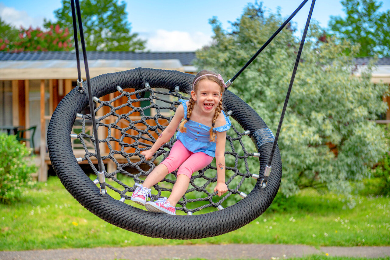 Smiling girl on bird's nest swing, camping CAPFUN Suzel in Sainte-Croix-en-Plaine.