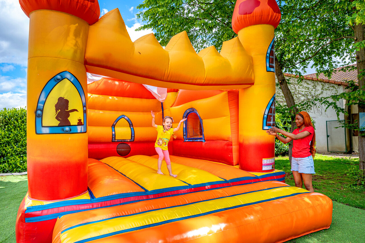Colorful inflatable bouncy castle with child and entertainer at CAPFUN Suzel campsite in Sainte-Croix-en-Plaine (68).