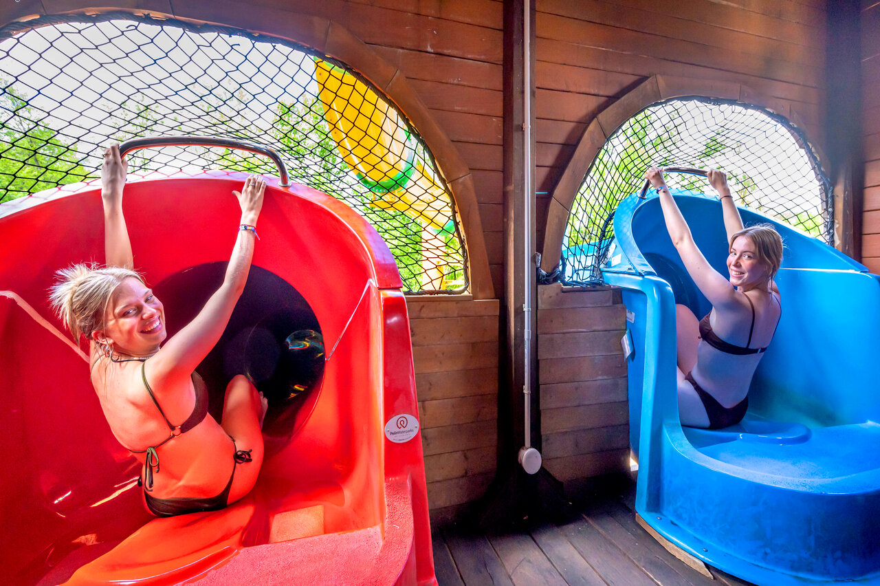 Smiling young women on water slides at CAPFUN Suzel campsite in Sainte-Croix-en-Plaine (68).