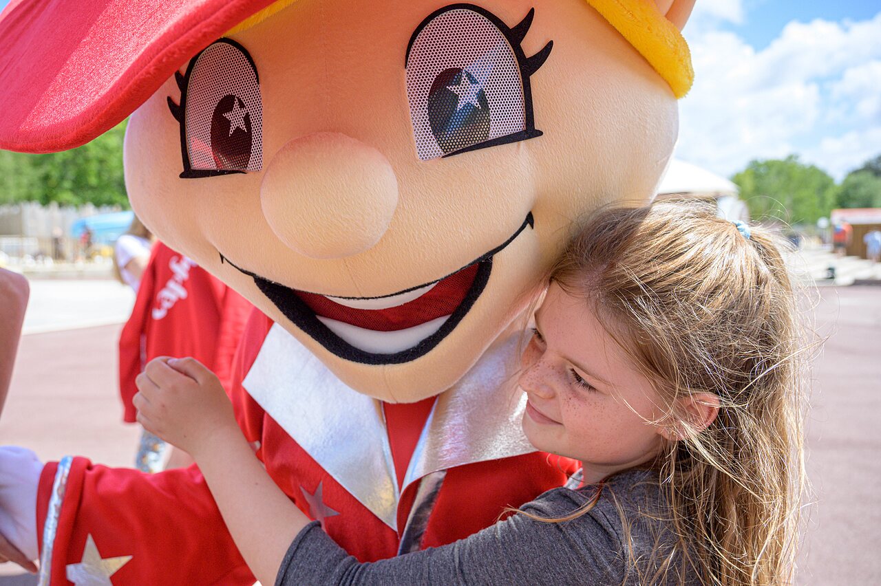 Smiling girl hugging mascot, entertainment at CAPFUN Talaris Vacances campsite in Lacanau (33).