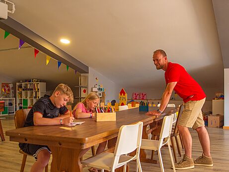 Children drawing at a table with an entertainer at CAPFUN Tecklenburg campsite in Tecklenburg-Leeden (49).