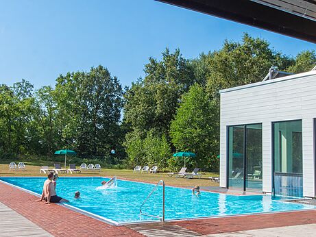 Outdoor swimming pool with bathers and modern building at CAPFUN Tecklenburg campsite (49).