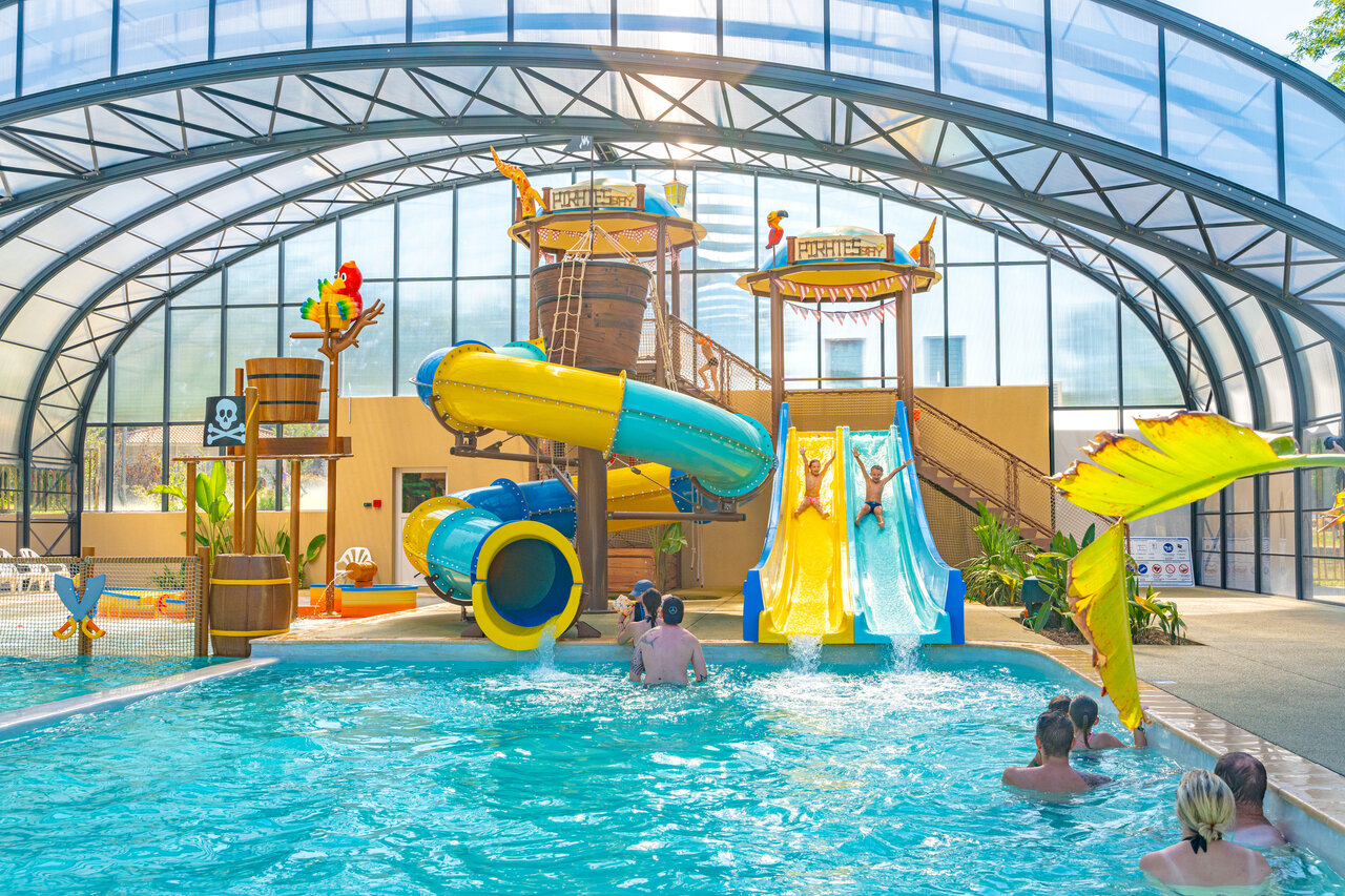 Covered water park, slides and water games at CAPFUN Temps Libre campsite in BOUGE CHAMBALUD (38).