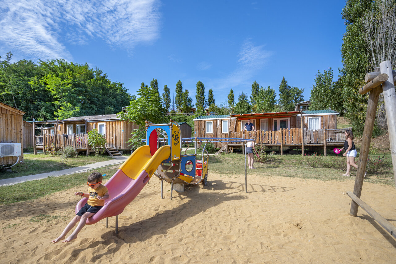 Playground with slide and Mobile-homes at CAPFUN Temps Libre campsite in BOUGE CHAMBALUD (38).