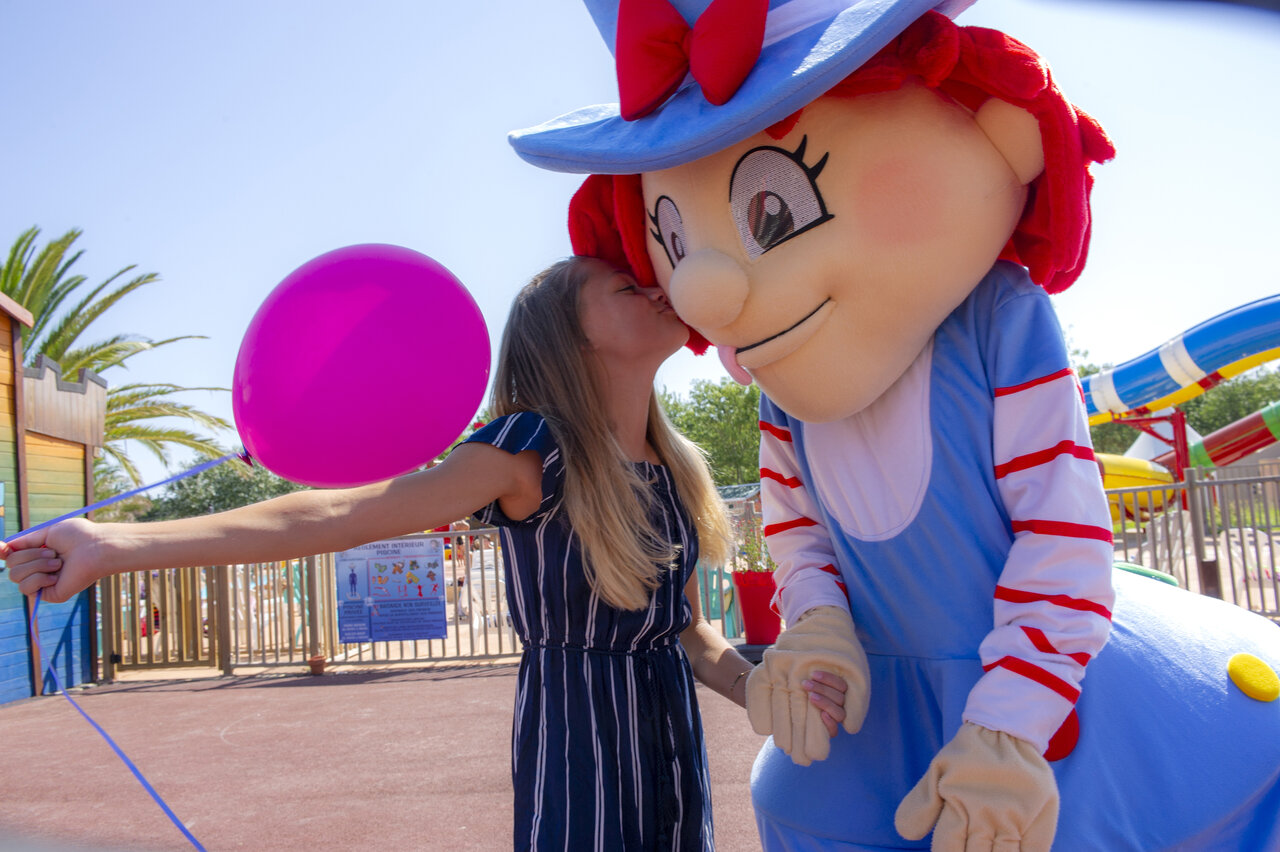 Child kissing mascot, pink balloon, games at CAPFUN Temps Libre campsite in BOUGE CHAMBALUD.