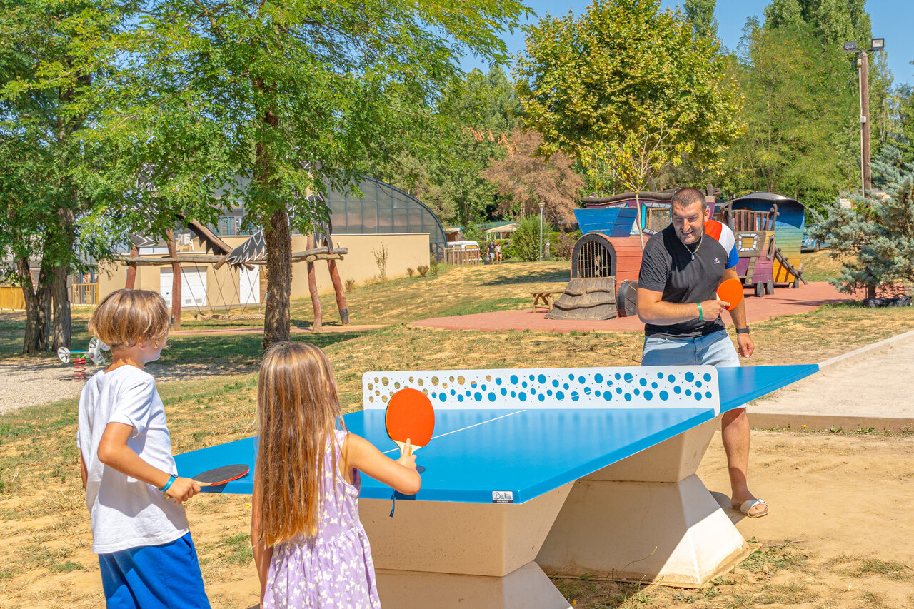 Family playing outdoor table tennis at CAPFUN Temps Libre campsite in BOUGE CHAMBALUD.
