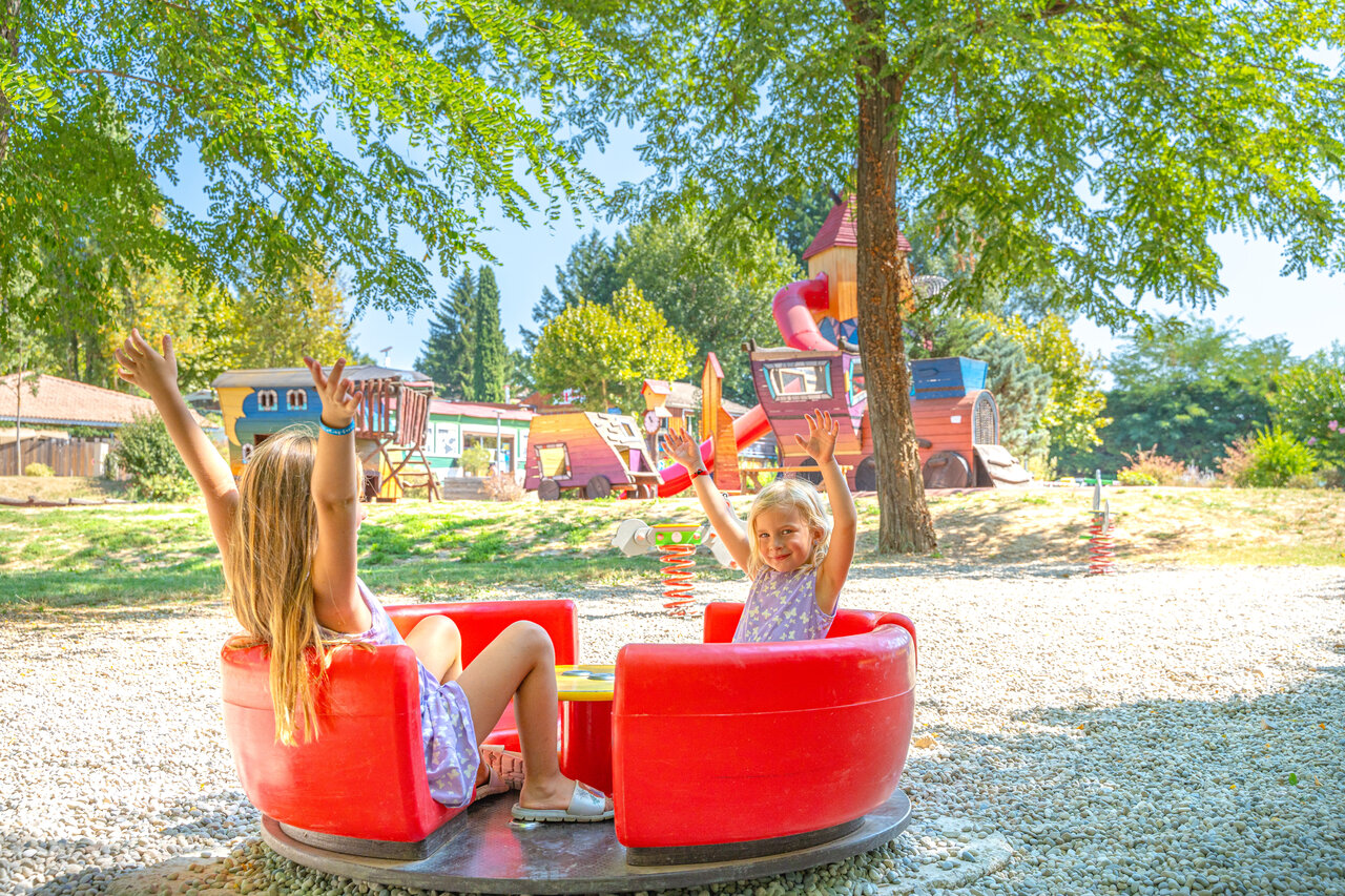 Children on spinning ride, playground at CAPFUN Temps Libre campsite in BOUGE CHAMBALUD (38).