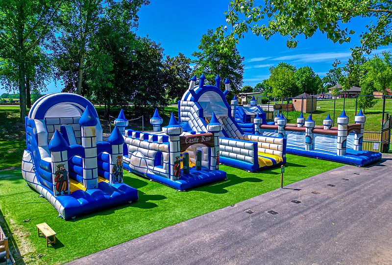 Inflatable bouncy castles and play course for children on green grass at CAPFUN Tensch Jolie campsite in Grostenquin (57).