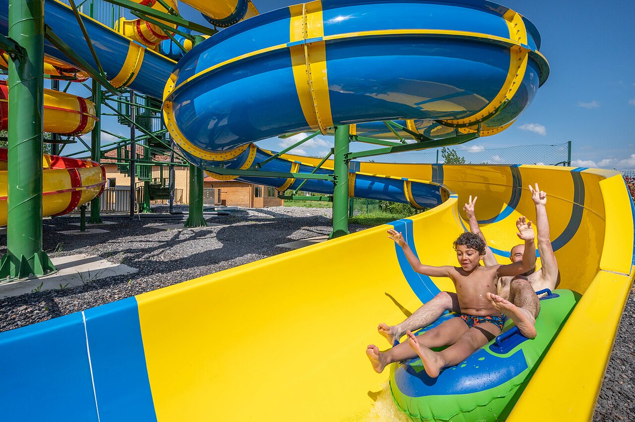 Giant water slide, two people on inflatable ring, at CAPFUN Tensch Jolie campsite in Grostenquin (57).