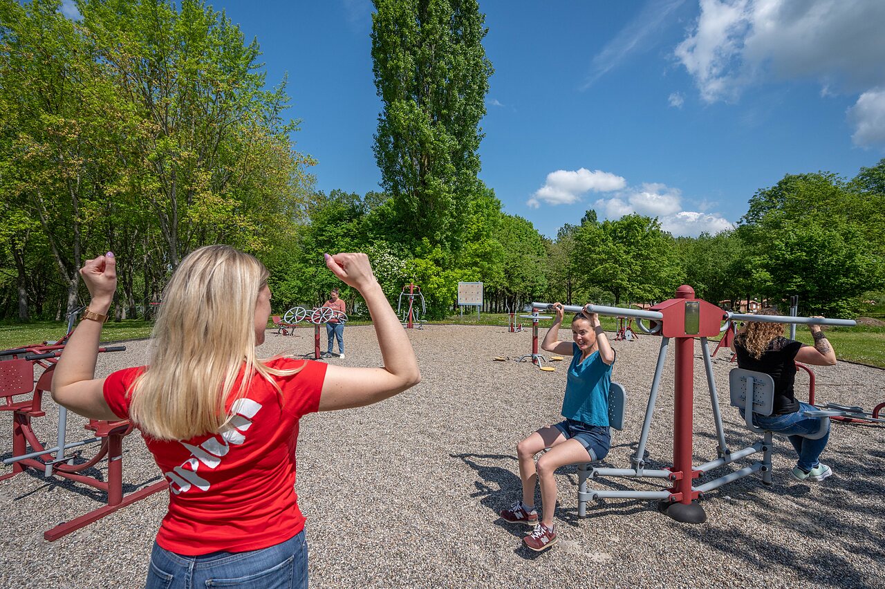 People on outdoor fitness equipment at CAPFUN Tensch Jolie campsite, Grostenquin (57).
