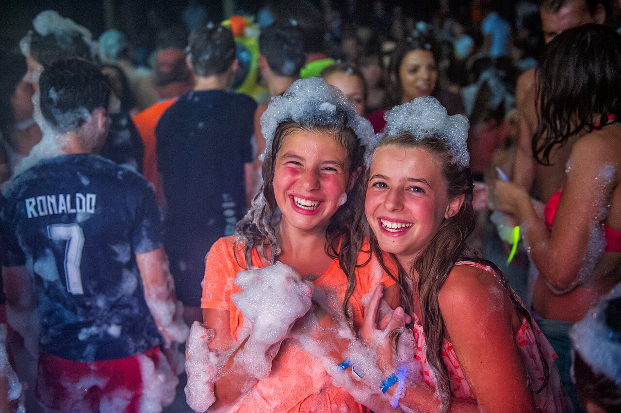 Two smiling girls at a lively foam party at CAPFUN Teorix campsite in MARSEILLAN PLAGE (34).