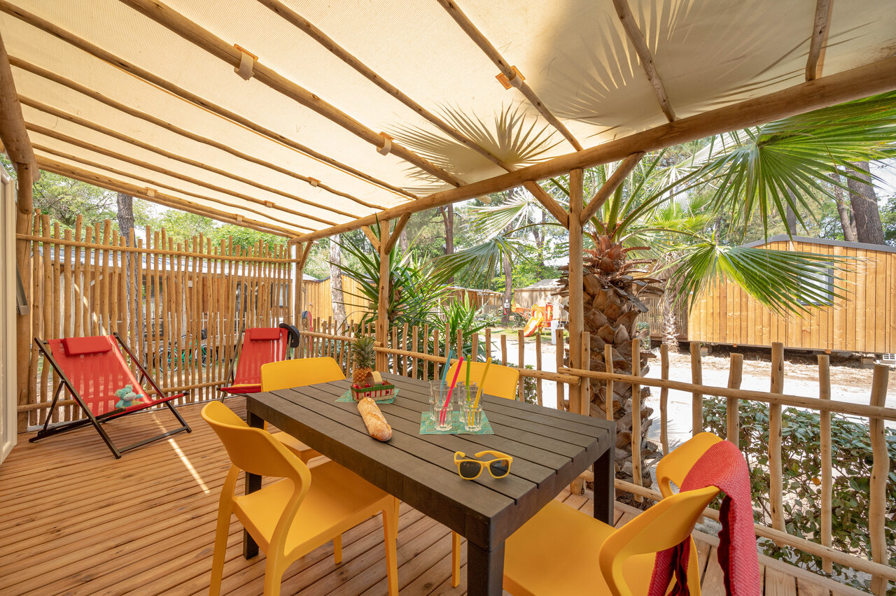 Shaded Mobile-home terrace with table and chairs at CLICOCHIC Texas campsite in Argel�s sur Mer (66).