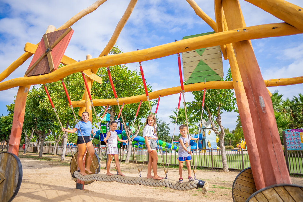 Children playing on rope bridge playground at CAPFUN Tordera-Nacions campsite in Malgrat de Mar.