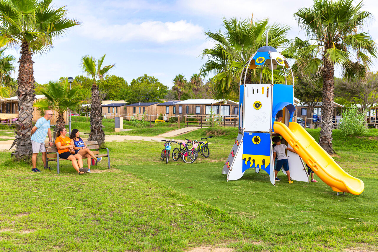 Rocket playground with slide, children and mobile homes at CAPFUN Tordera-Nacions campsite in Malgrat de Mar.