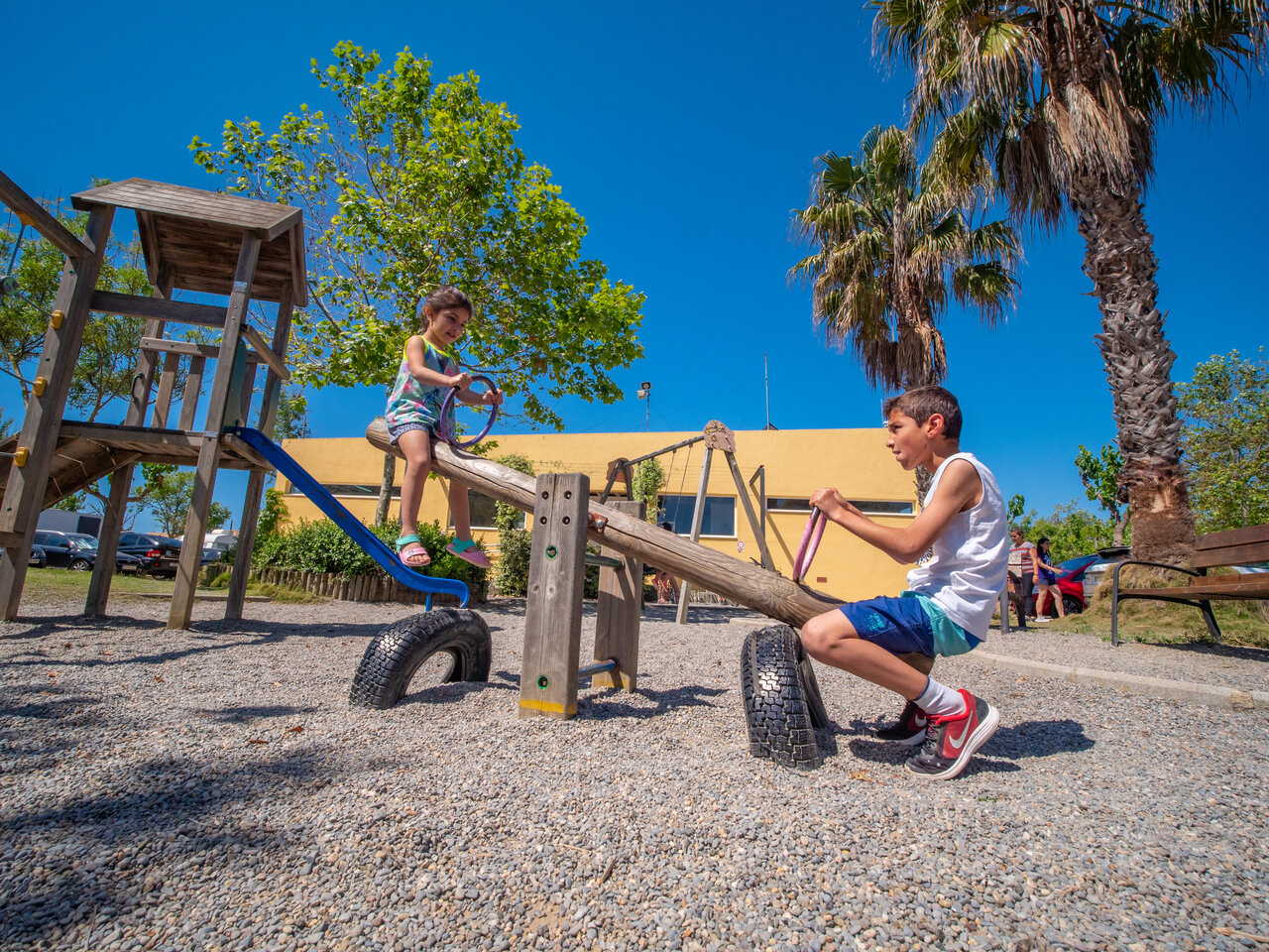 Playground with children on seesaw at CAPFUN Tordera-Nacions campsite in Malgrat de Mar.