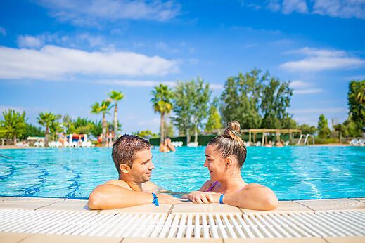 Smiling couple in the outdoor swimming pool at CAPFUN Tordera-Nacions campsite in Malgrat de Mar.