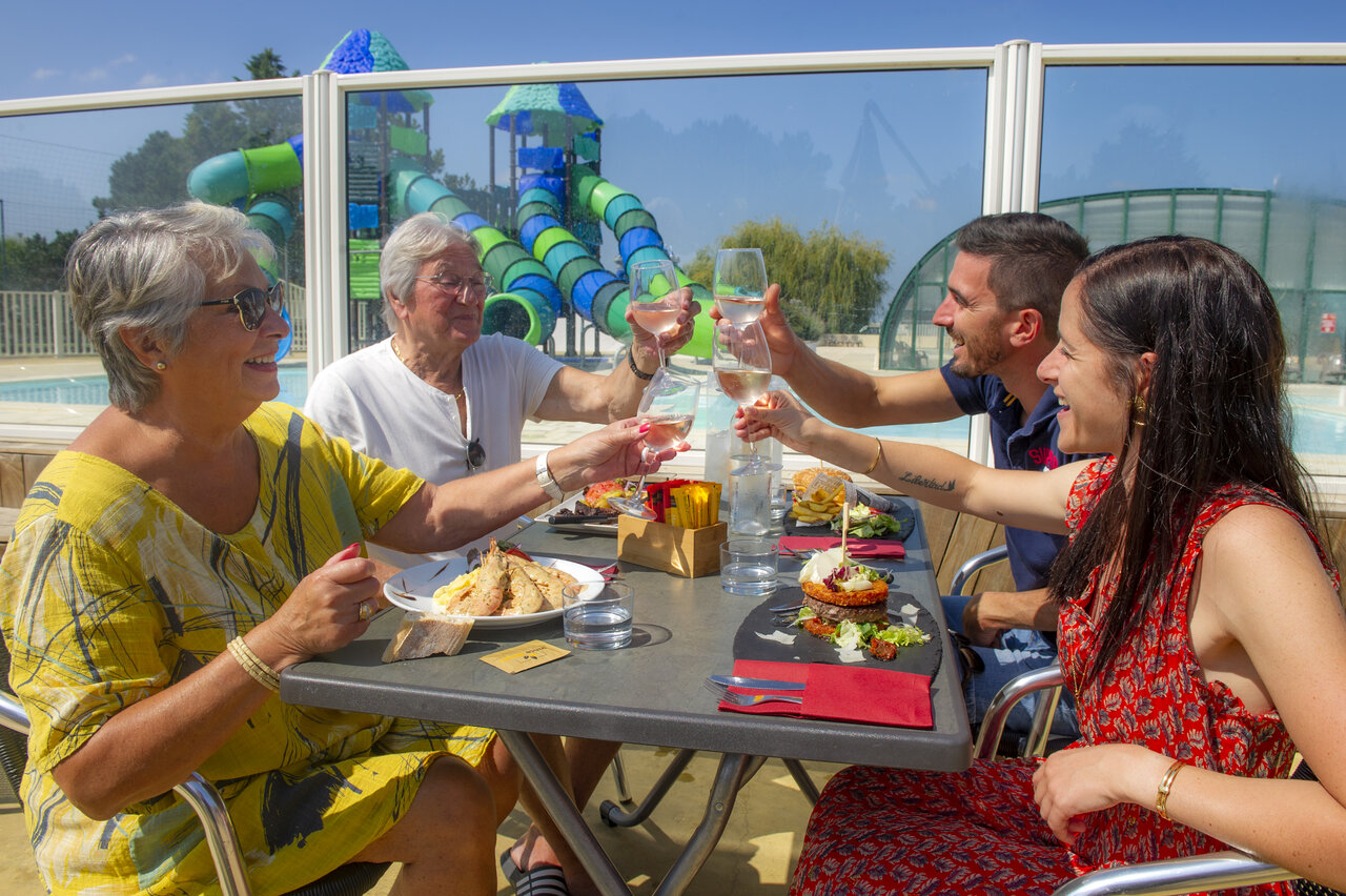 Family toasting on terrace, pool and slides at CAPFUN Celeste in Breuillet (17).