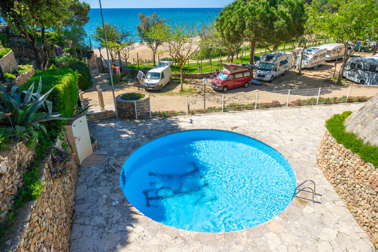 Round swimming pool, sandy beach and caravan pitches at CAPFUN Treumal campsite in Platja d'Aro (17).