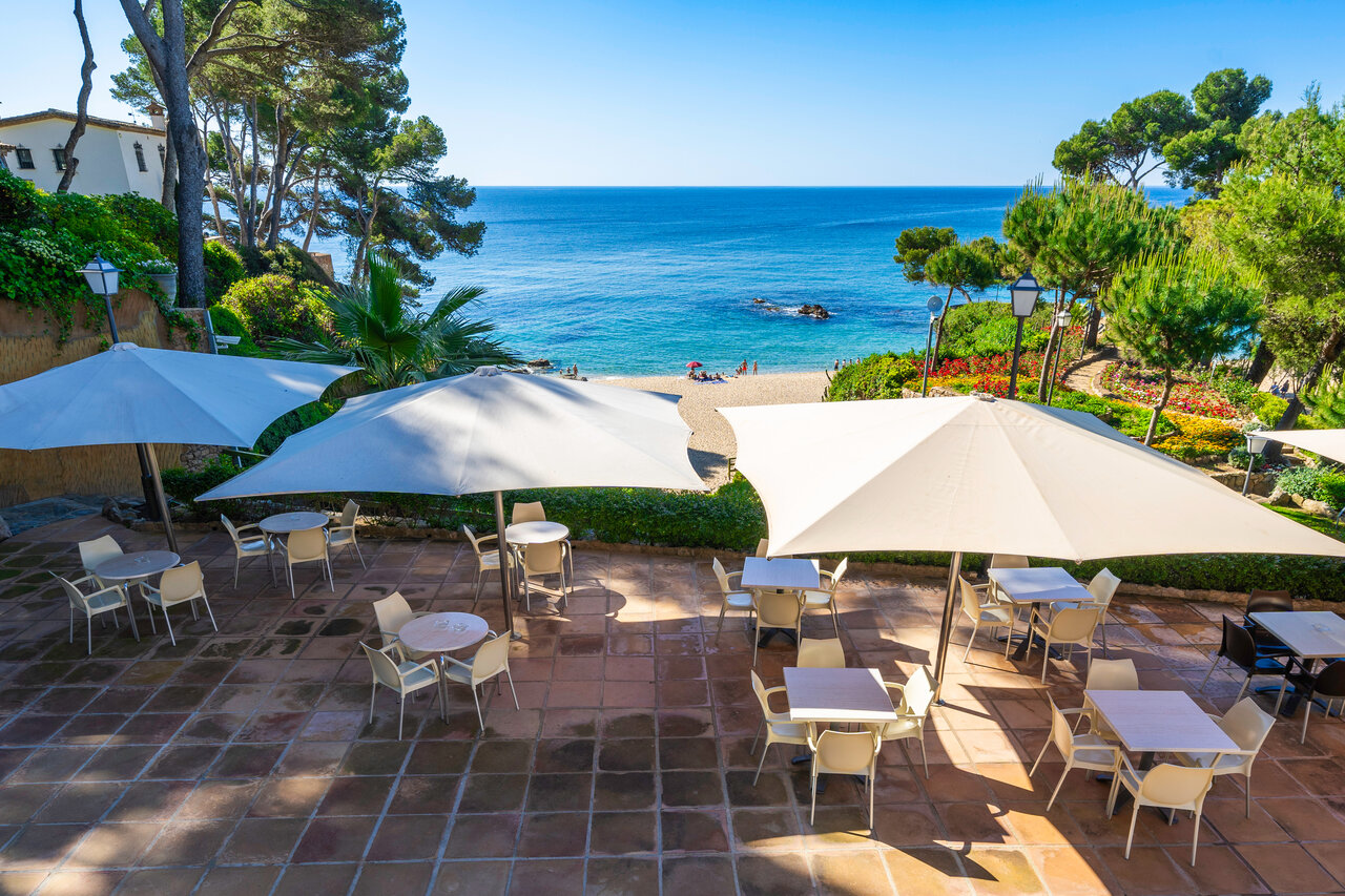 Restaurant terrace with parasols, beach and Mediterranean Sea at CAPFUN Treumal campsite in Platja d'Aro (17).