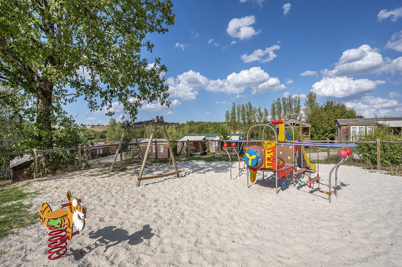 Playground with swing set, colorful structure and Mobile homes at CAPFUN Ullule campsite in Tournon d'Agenais (47).
