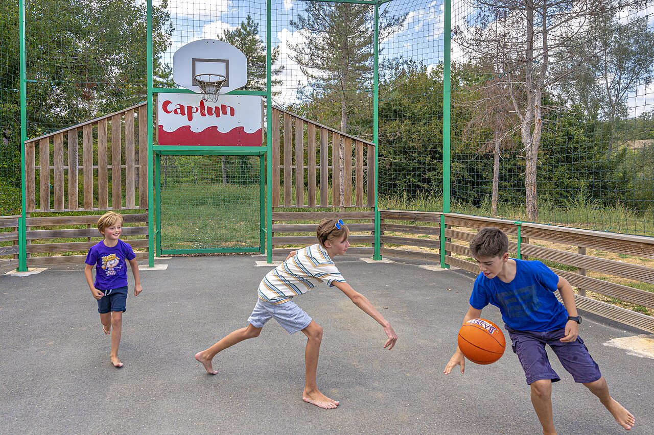 Multisport court with children playing basketball at CAPFUN Ullule campsite in Tournon d'Agenais (47).